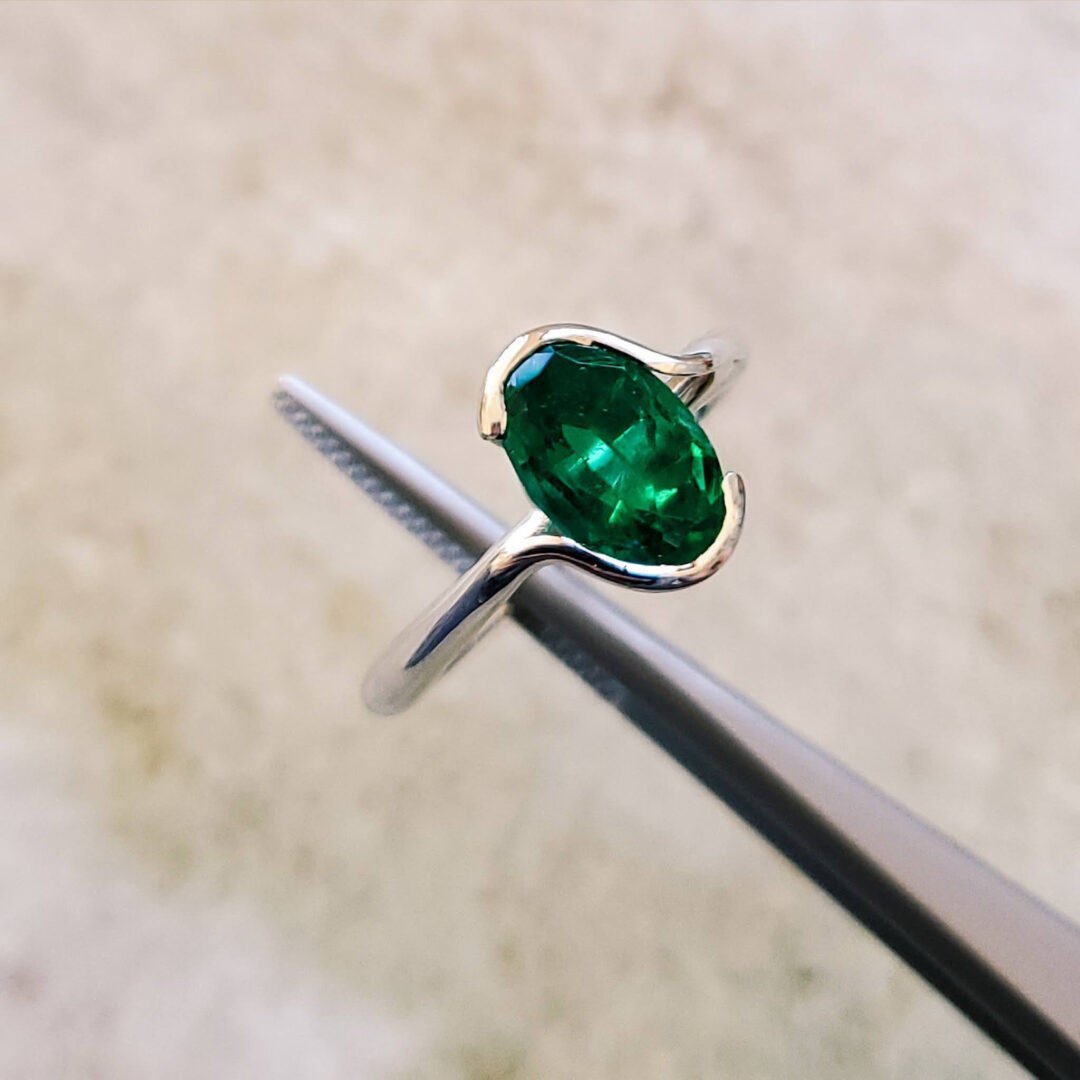Se trata de una sortija tipo solitario realizada en oro blanco de ley (750 milésimas). Presenta un centro de esmeralda natural talla oval cuyo peso total es de 1.39 cts. y su valorado origen Colombia.